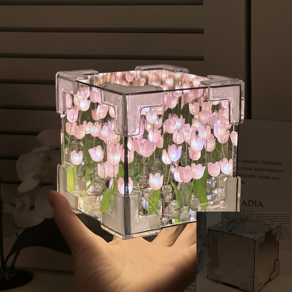 Transparent cube night light with floral design, held by a hand against a neutral background.