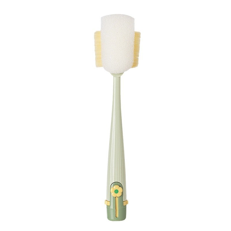 A dual-sided cleaning brush with a pale sage green handle, a white foam head, and yellow bristles on a solid white background.