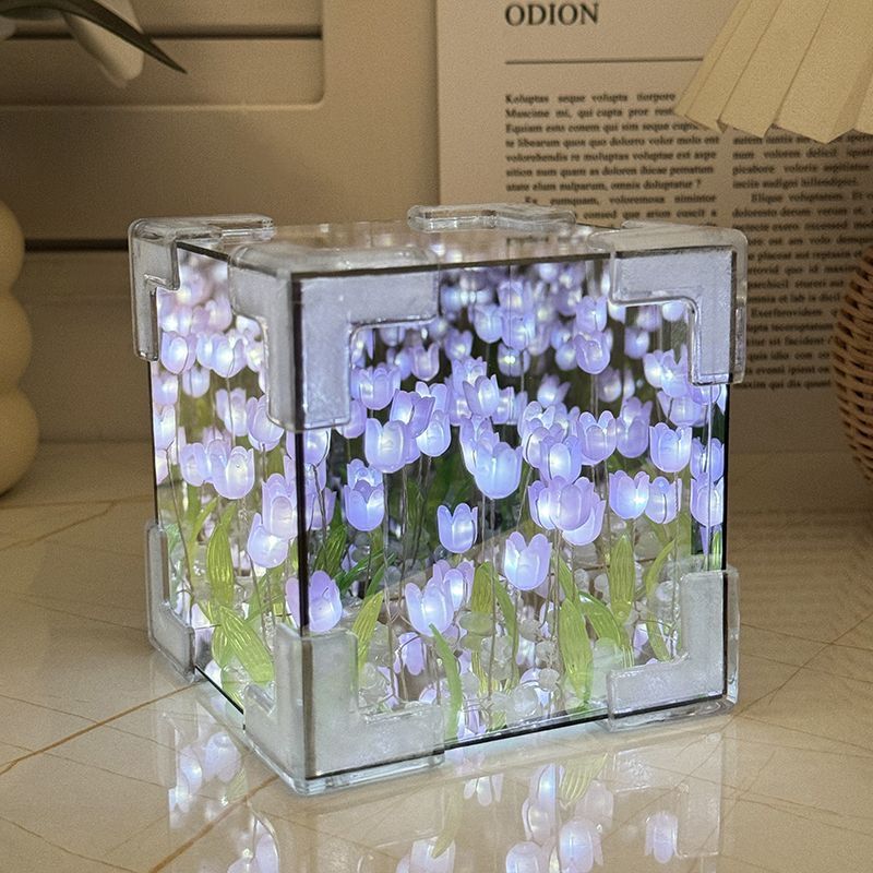 Decorative glass cube with LED lights and tulip design on a reflective surface.