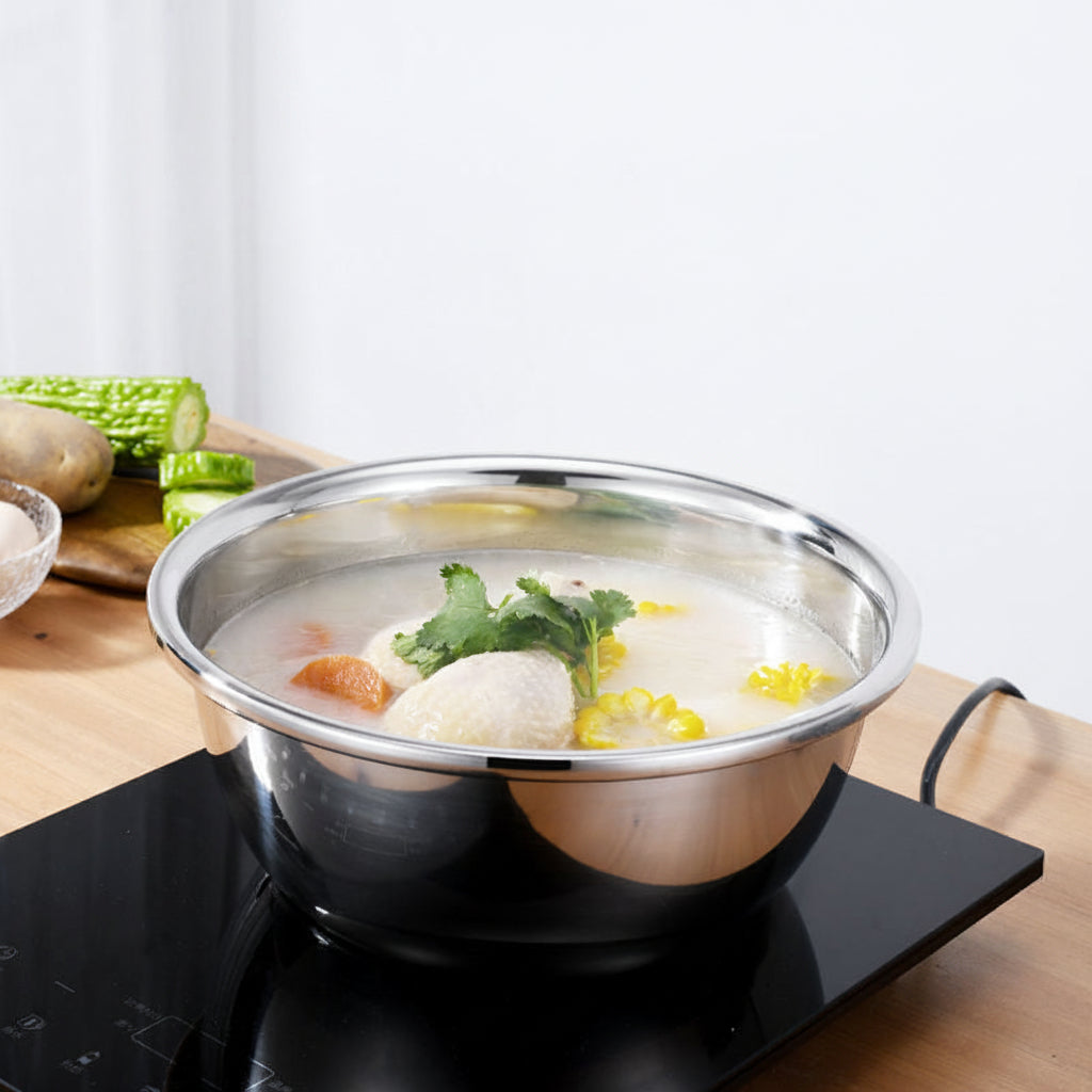 Stainless steel pot with soup on an electric stove, surrounded by vegetables.