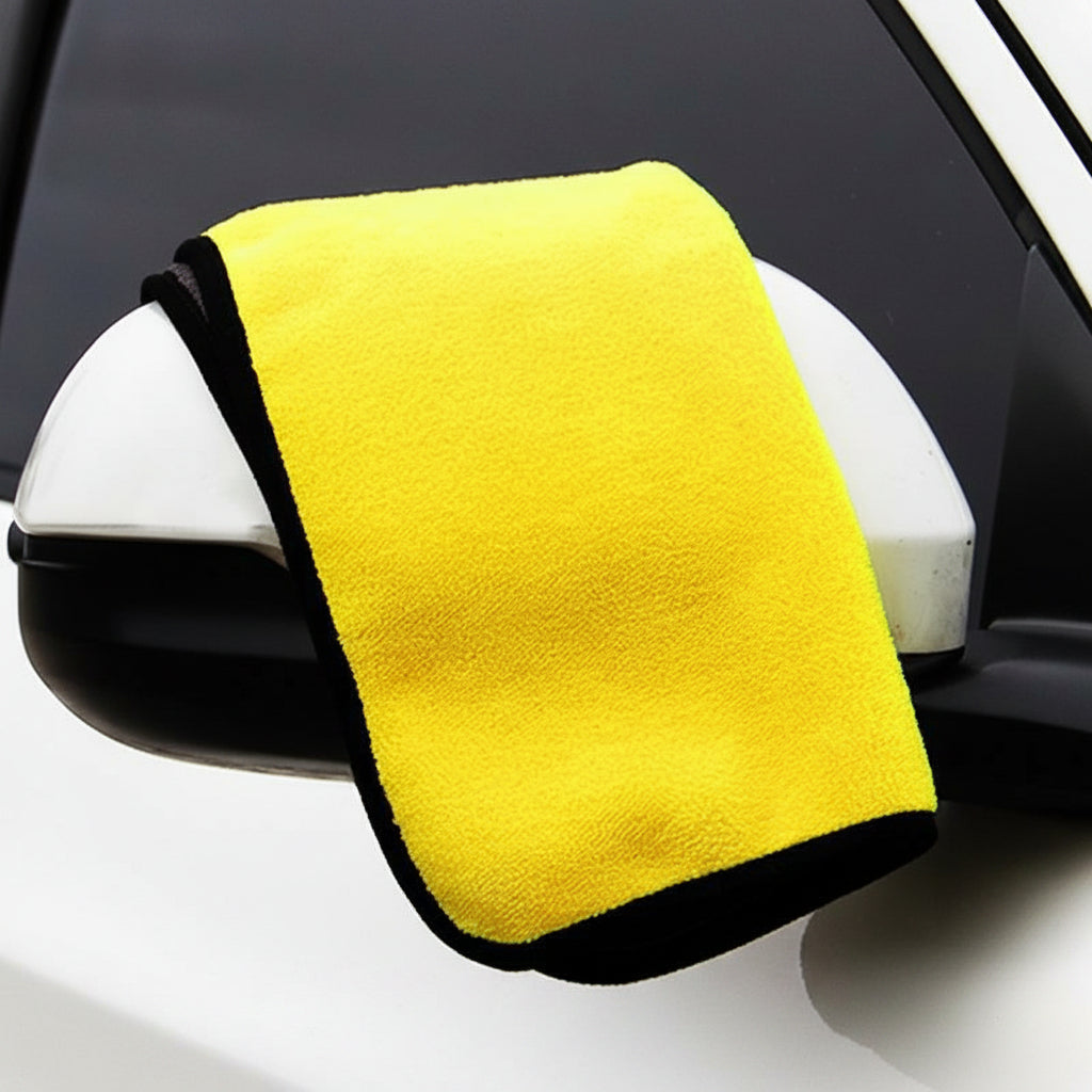 Yellow microfiber towel draped over a car mirror with a black border.