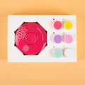 Manicure tool set with pink circular component and color samples on a beige background