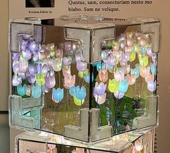 Decorative glass block with colorful tulip-shaped lights inside, on a wooden surface.